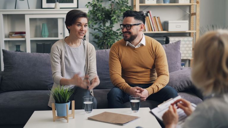 A couple discussing with a therapist during a counseling session indoors.